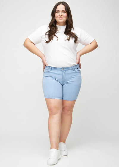 Fuldt billede af en plus-size model i lyseblå skinny short shorts.