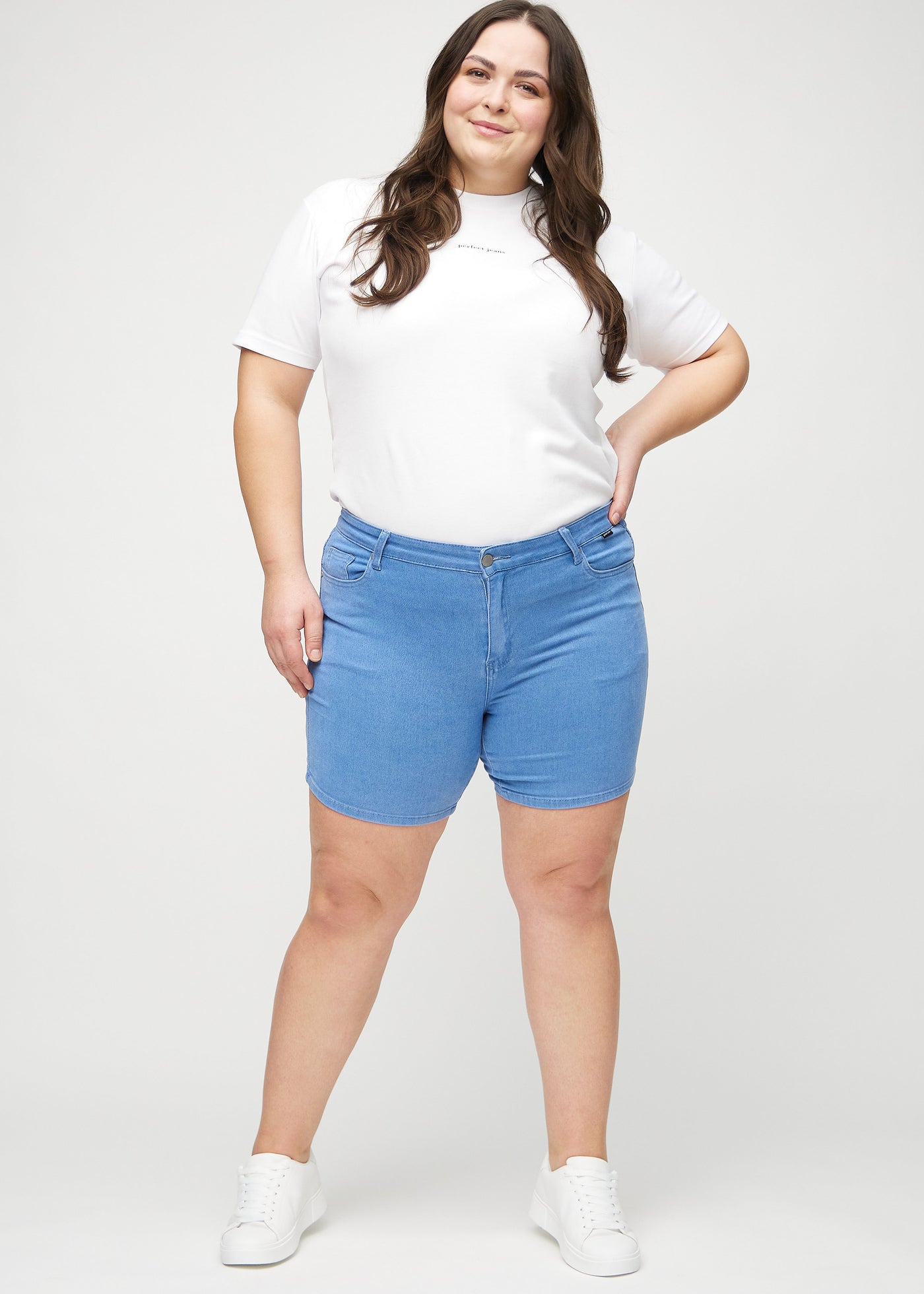 Fuldt billede af en plus-size model i blå skinny short shorts.