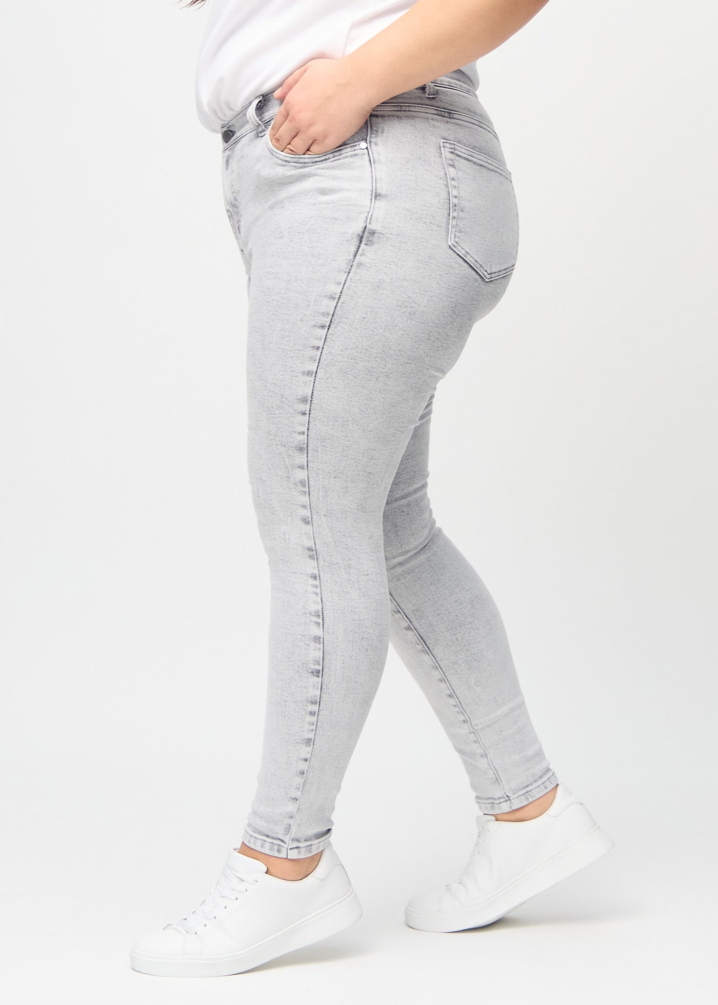 Lysegrå denim skinny jeans set fra siden på en plus-size model.