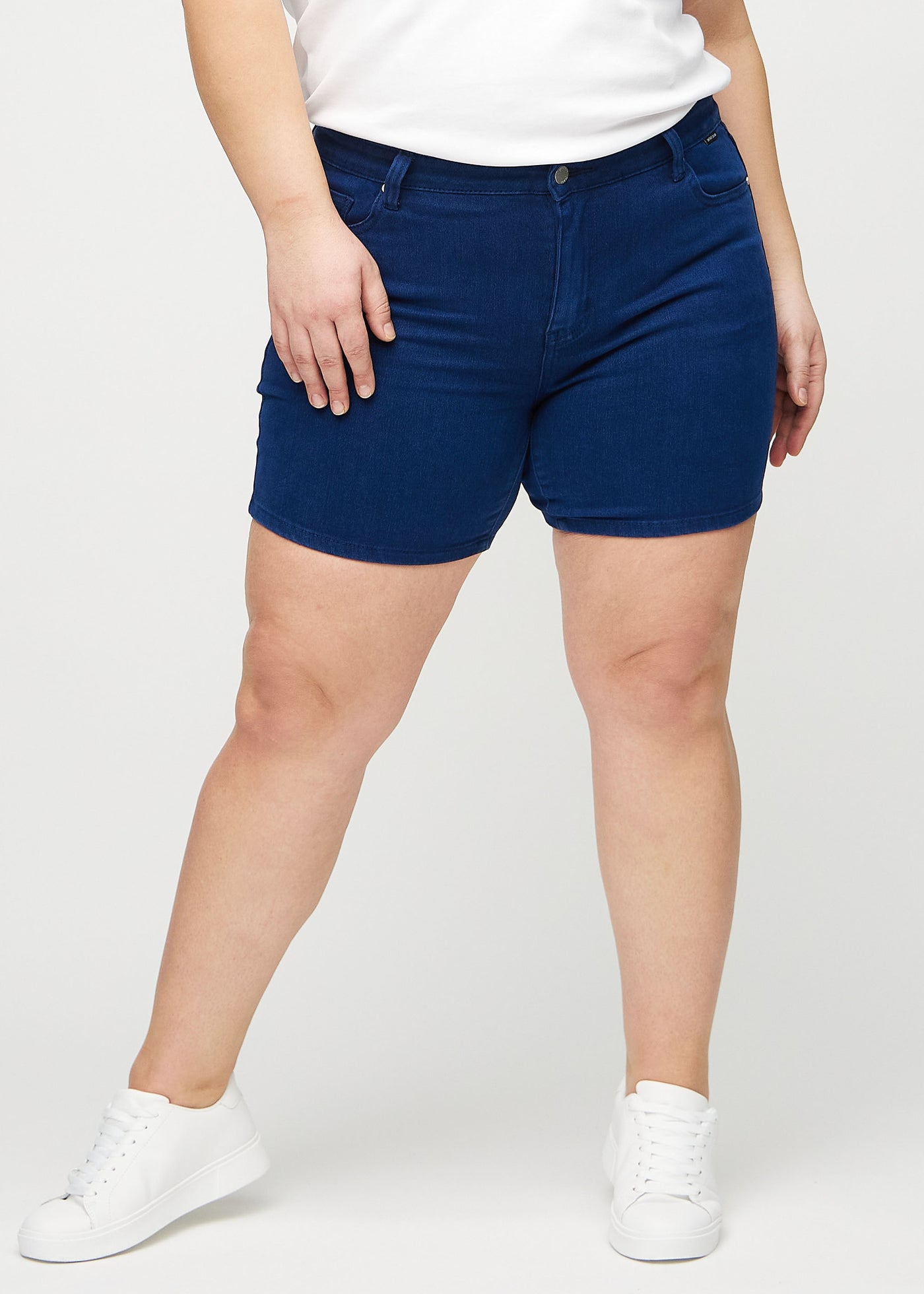 Mørkeblå skinny short shorts, modelnavn Royals, som sidder tæt til, og slutter midt på låret på en plus-size model, set forfra.