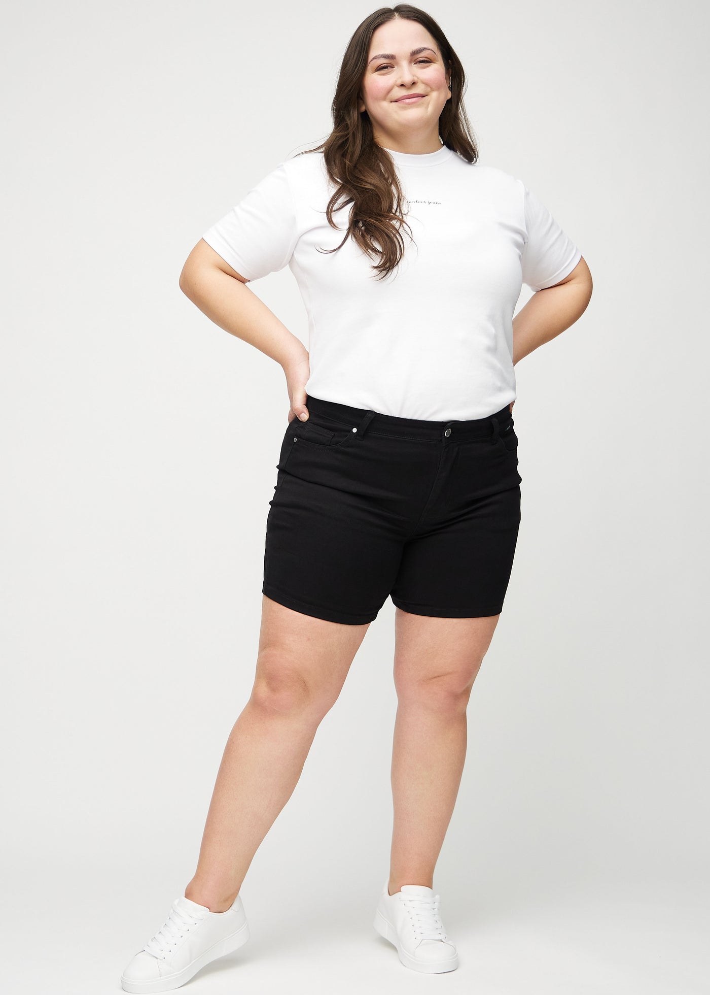 Fuldt billede af en plus-size model i sorte skinny short shorts.