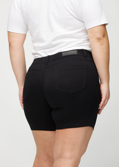 Sorte skinny short shorts set bagfra tæt på en plus-size model for at vise detaljer.