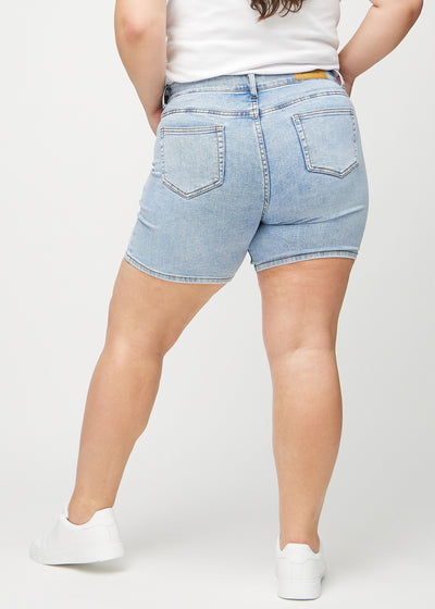 Lys denim skinny short shorts set bagfra på en plus-size model, så man kan se hele produktet.