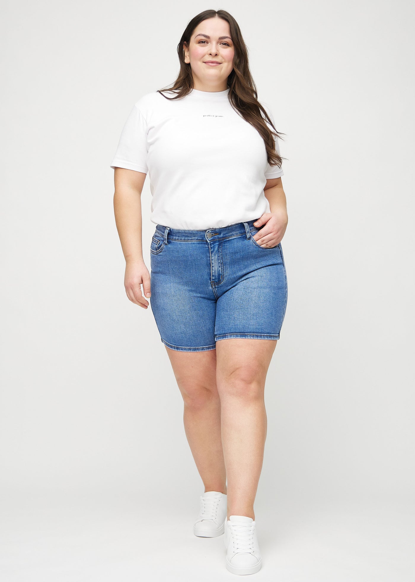 Fuldt billede af en plus-size model i denim skinny short shorts.