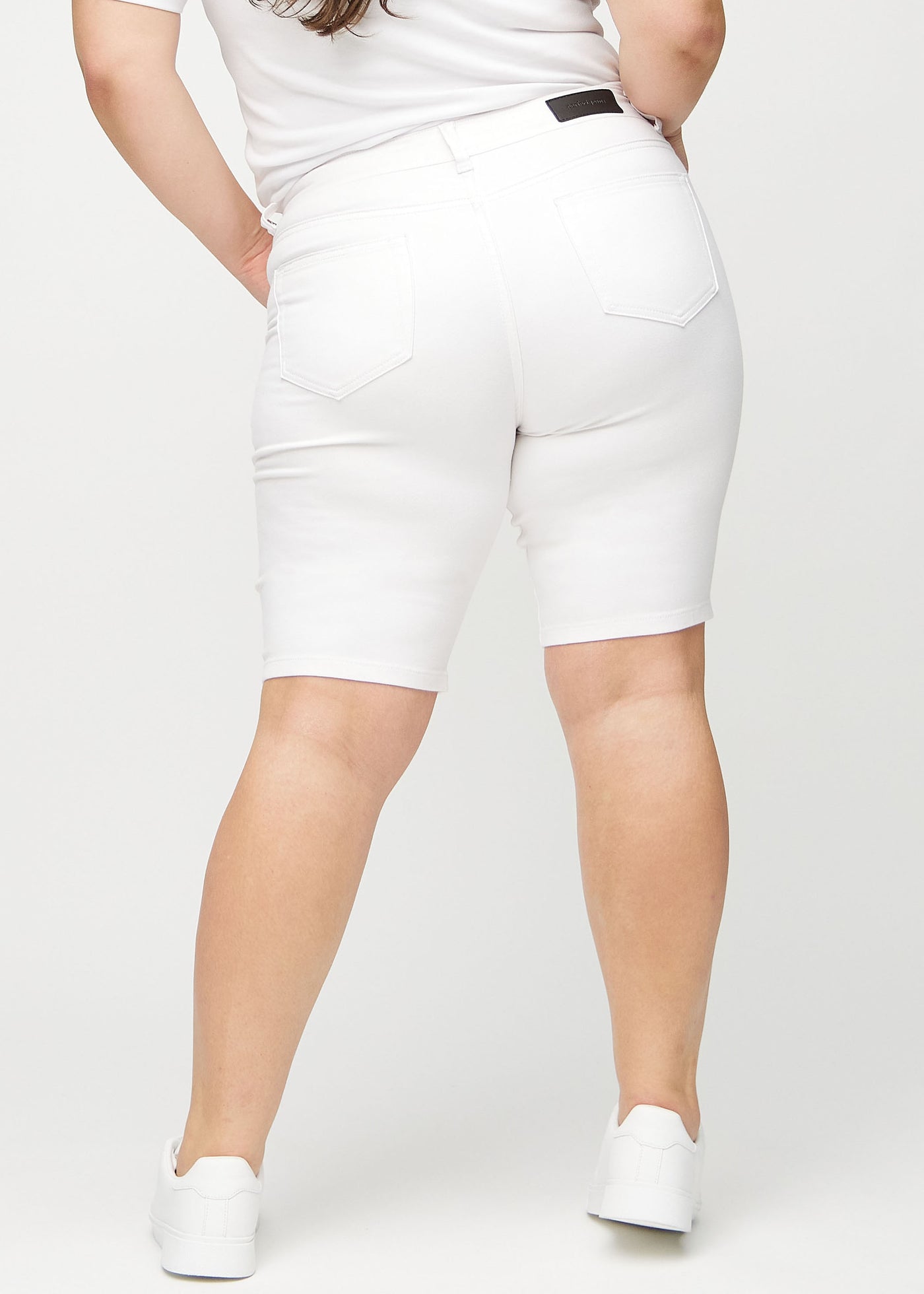 Hvide skinny middle shorts set bagfra på en plus-size model, så man kan se hele produktet.