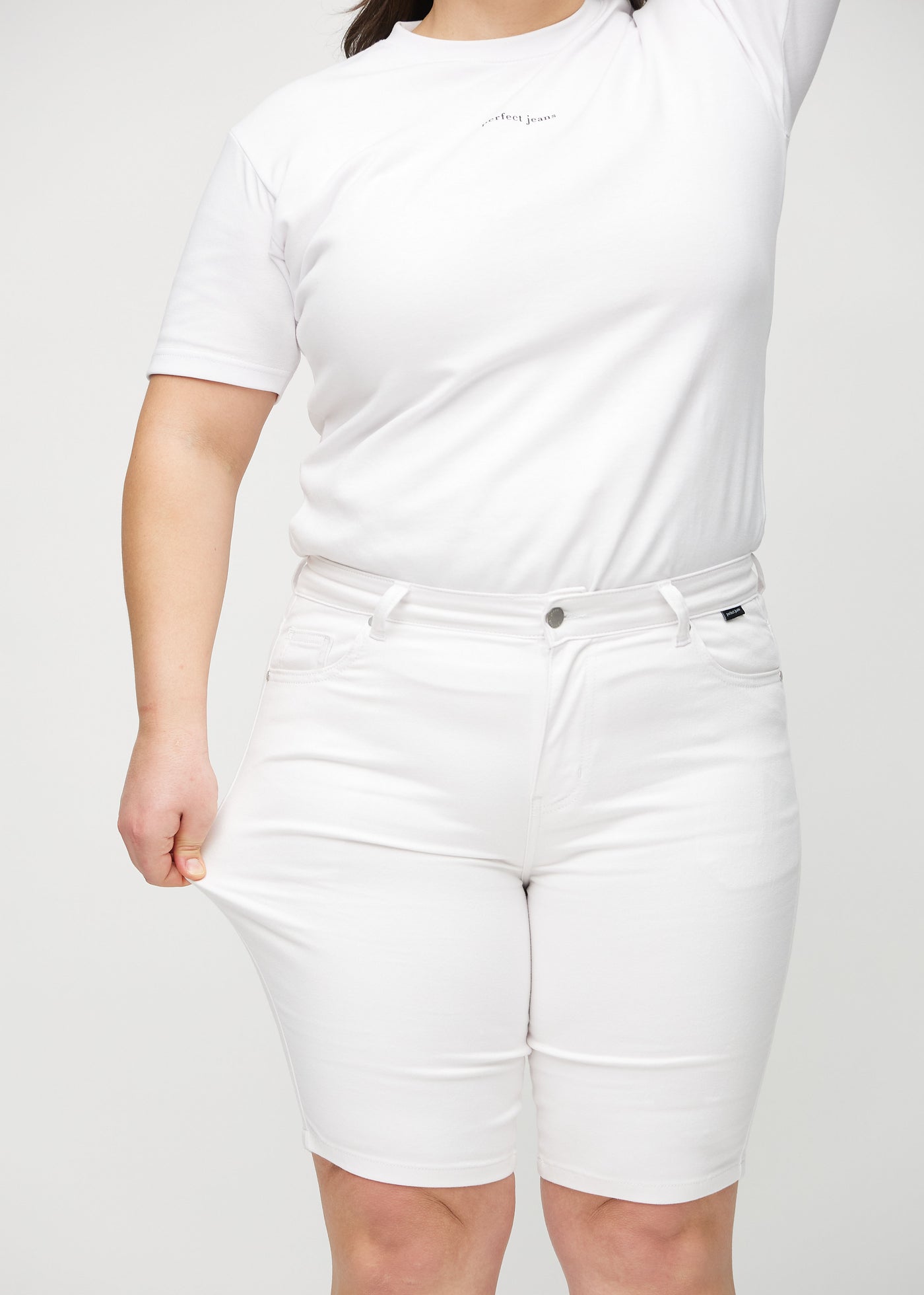 Plus-size model strækker shortsene ved låret for at vise stretch.