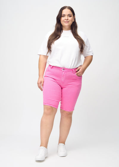 Fuldt billede af en plus-size model i lyserøde skinny middle shorts.