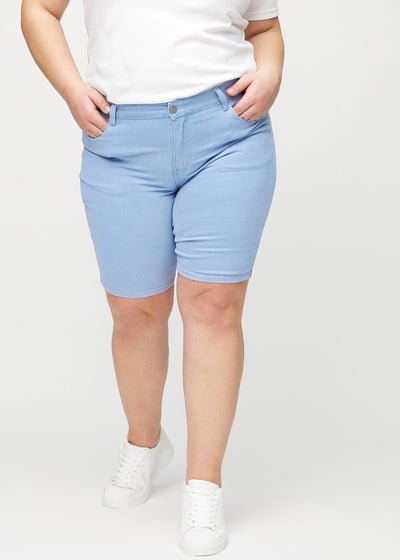 Lyseblå skinny middle shorts, modelnavn Skies, som sidder tæt til låret og slutter lige over knæet på en plus-size model, set forfra.