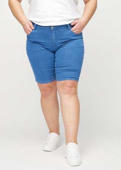 Blå skinny middle shorts, modelnavn Geraniums, som sidder tæt til låret og slutter lige over knæet på en plus-size model, set forfra.