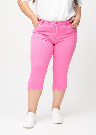 Lyserøde skinny capris, modelnavn Flamingos, som sidder tæt til benet på en plus-size model, set forfra.