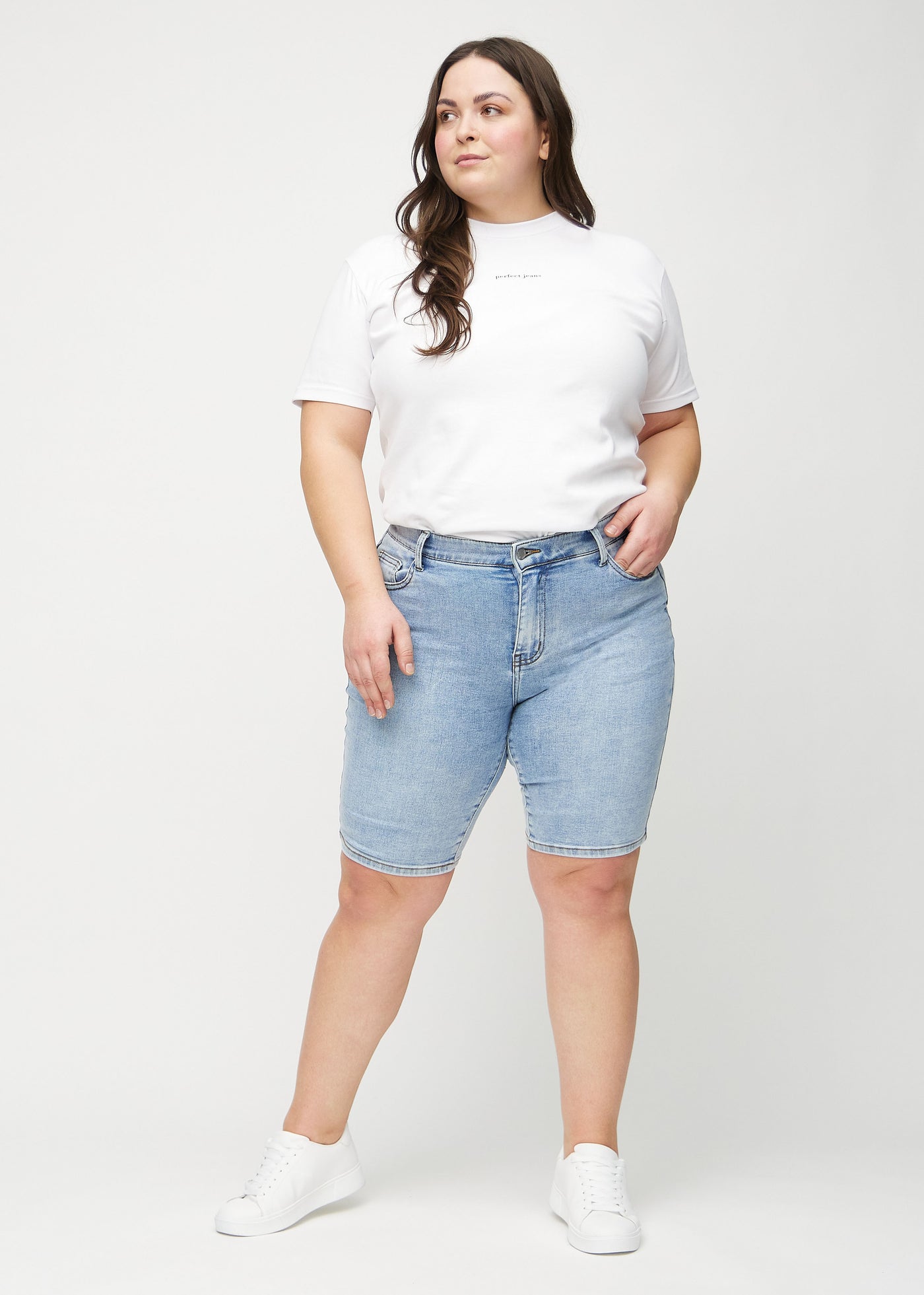 Fuldt billede af en plus-size model i lys denim skinny middle shorts.