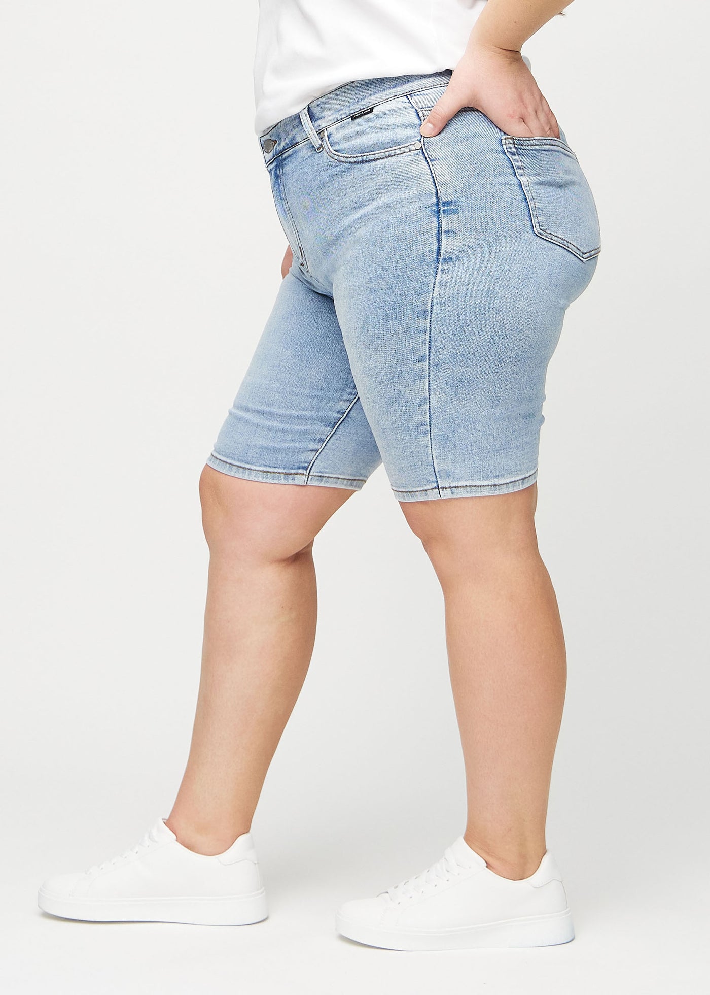 Lys denim skinny middle shorts set fra siden på en plus-size model.