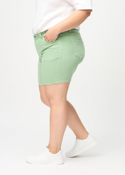 Lysegrønne skinny short shorts set fra siden på en plus-size model.