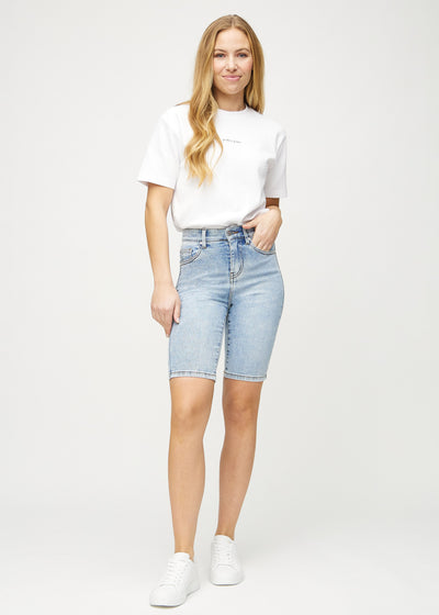 Fuldt billede af model i lys denim skinny middle shorts.