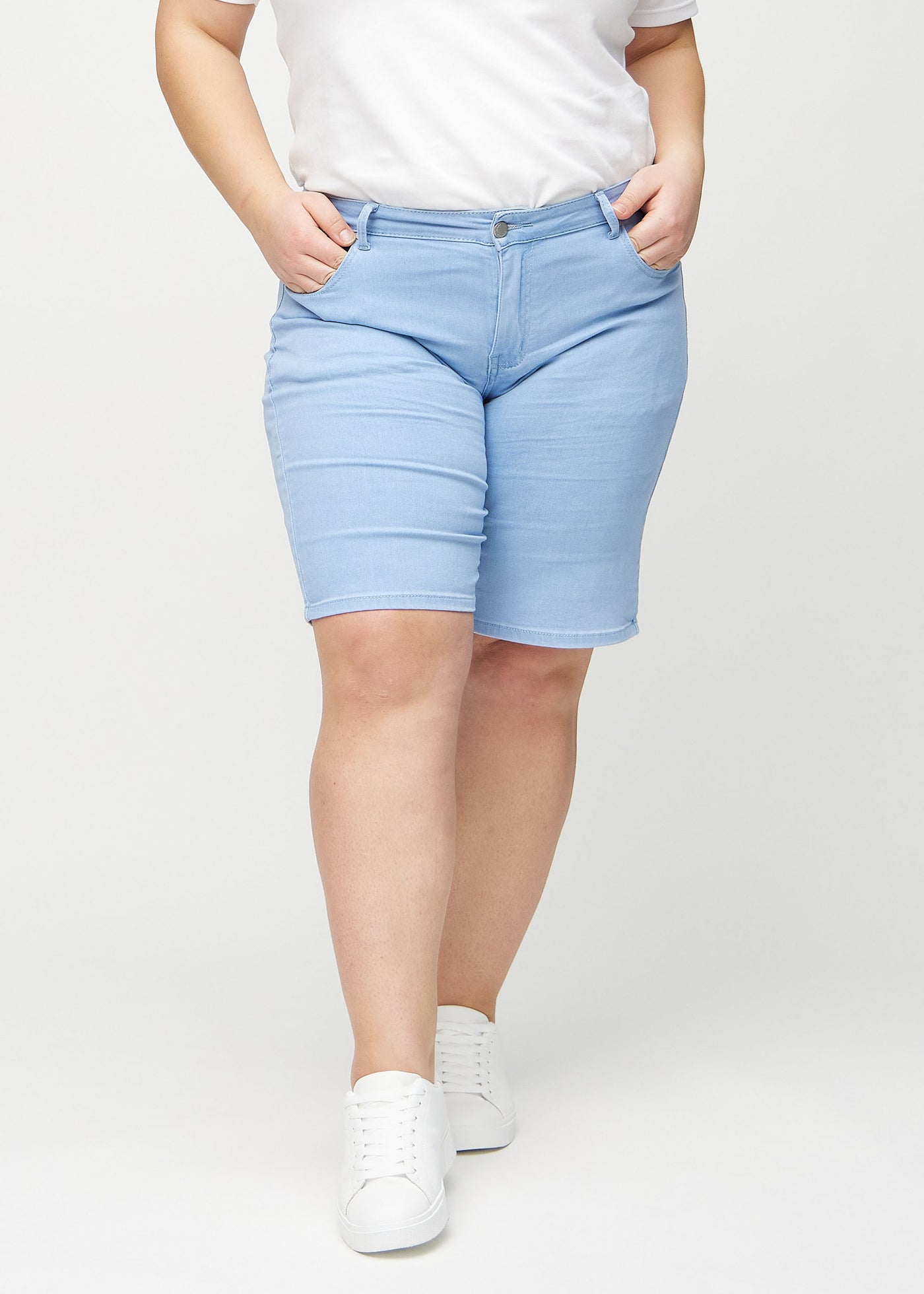 Lyseblå regular middle shorts, modelnavn Skies, som går lige ned langs benet og slutter lige over knæet på en plus-size model, set forfra.