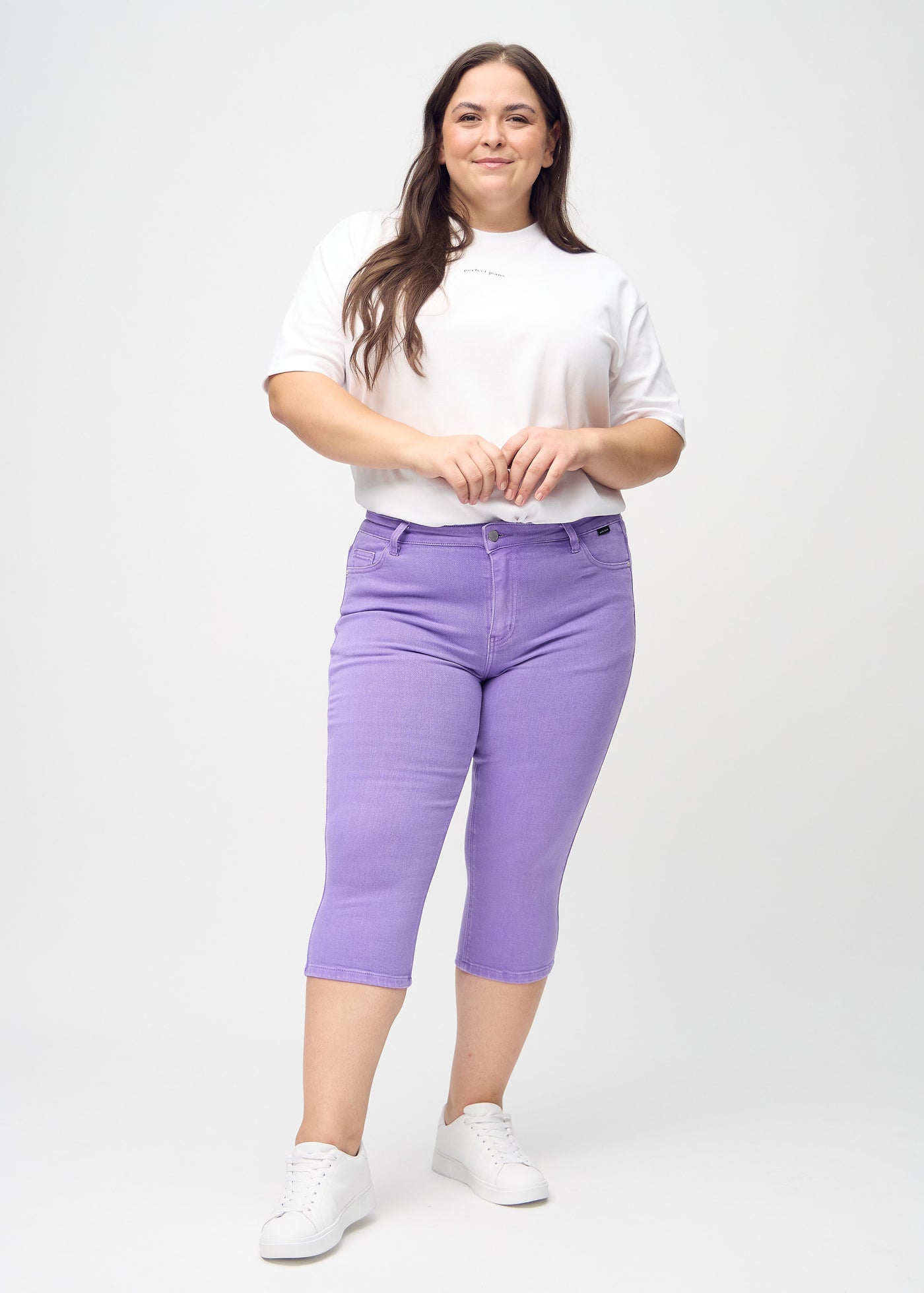 Fuldt billede af en plus-size model i lilla skinny capris.