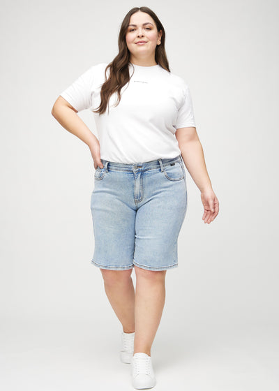 Fuldt billede af en plus-size model i lys denim regular middle ultra high rise shorts.