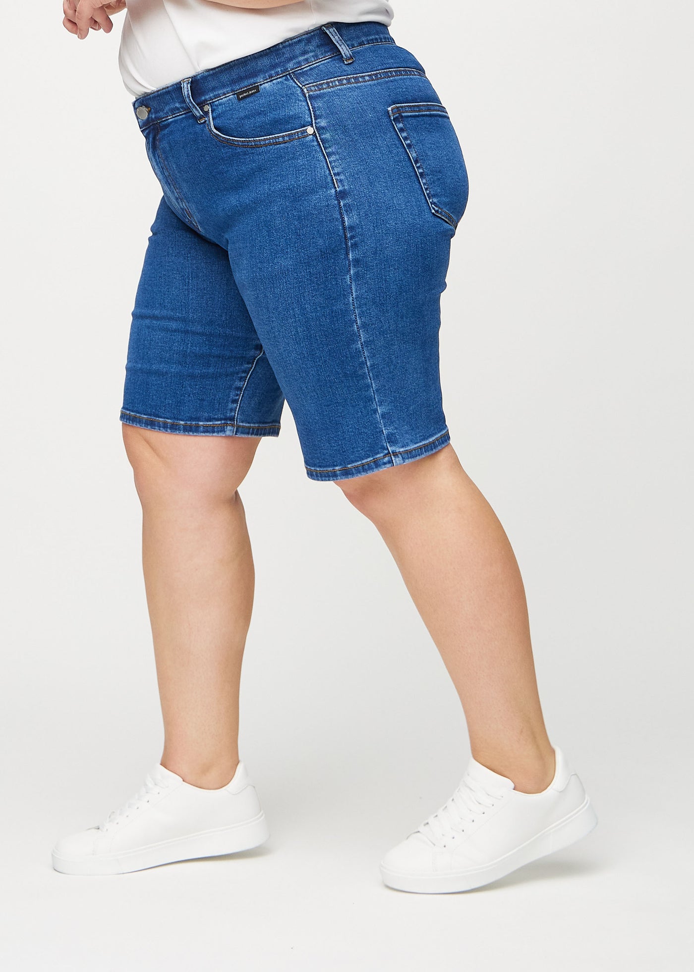 Mørk denim regular middle ultra high rise shorts set fra siden på en plus-size model.