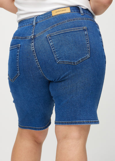 Mørk denim regular middle ultra high rise shorts set bagfra tæt på en plus-size model for at vise detaljer.