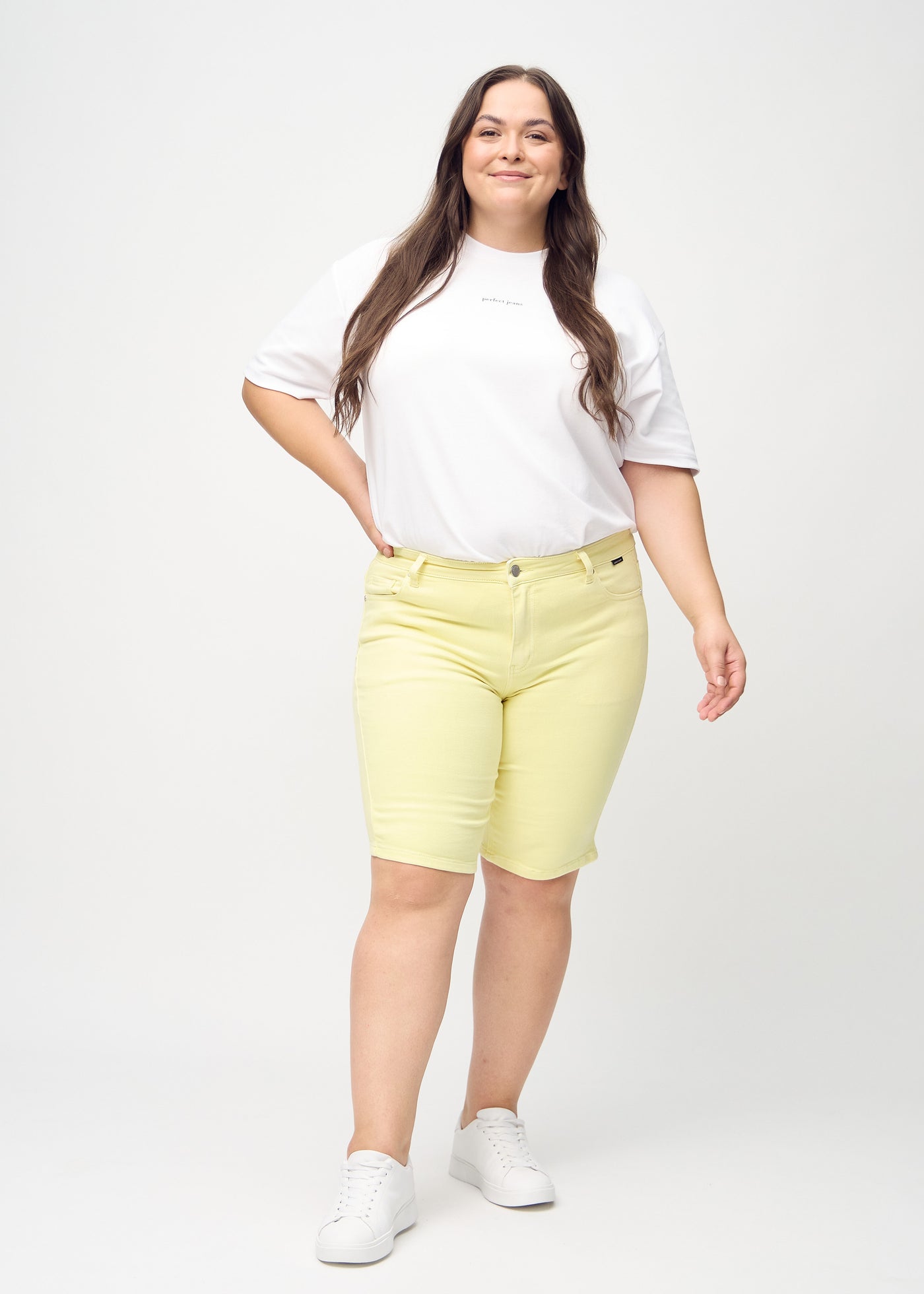 Fuldt billede af en plus-size model i lysegule skinny middle shorts.