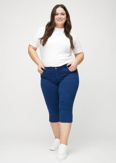 Fuldt billede af en plus-size model i mørkeblå skinny capris.