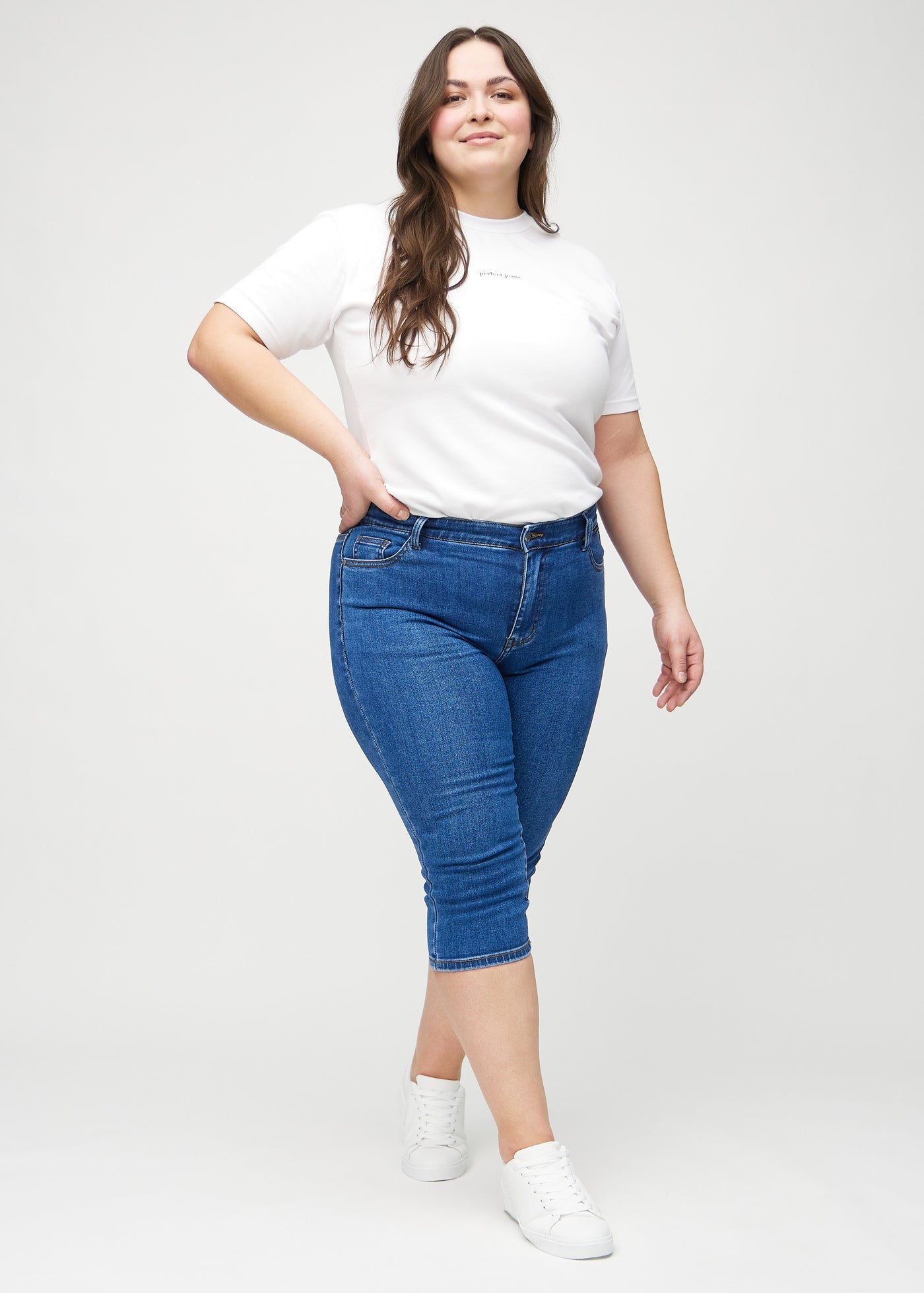 Fuldt billede af en plus-size model i mørk denim skinny capris.