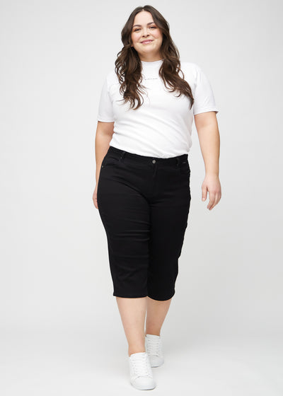 Fuldt billede af en plus-size model i sorte regular capris.