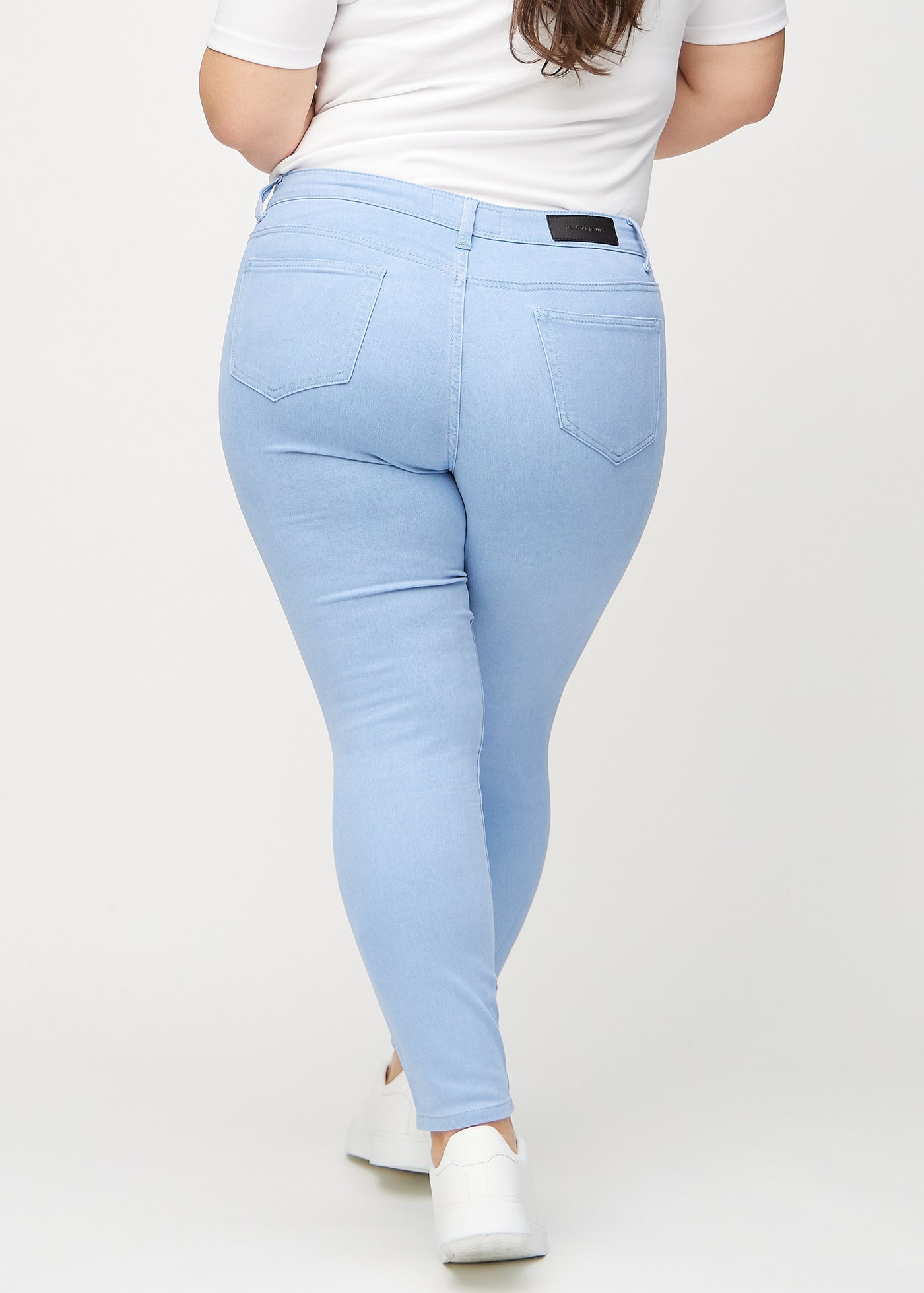 Lyseblå skinny jeans set bagfra på en plus-size model, så man kan se hele produktet.