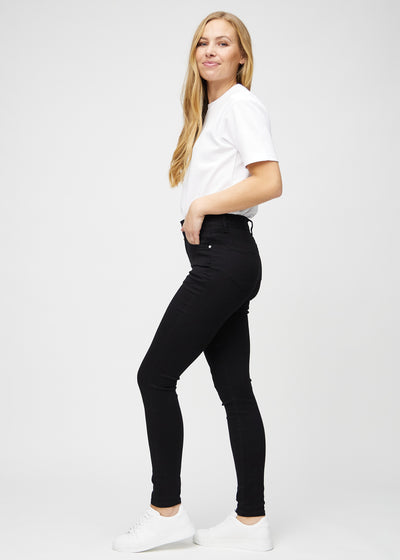 Sorte skinny jeans set fra siden på model.