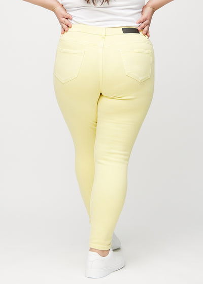 Lysegule skinny jeans set bagfra på en plus-size model, så man kan se hele produktet.