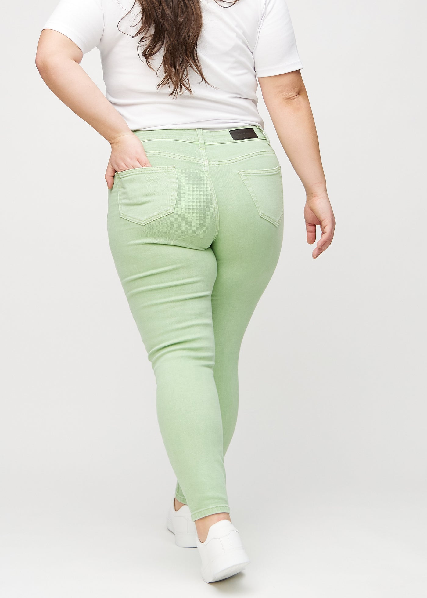 Lysegrønne skinny jeans set bagfra på en plus-size model, så man kan se hele produktet.