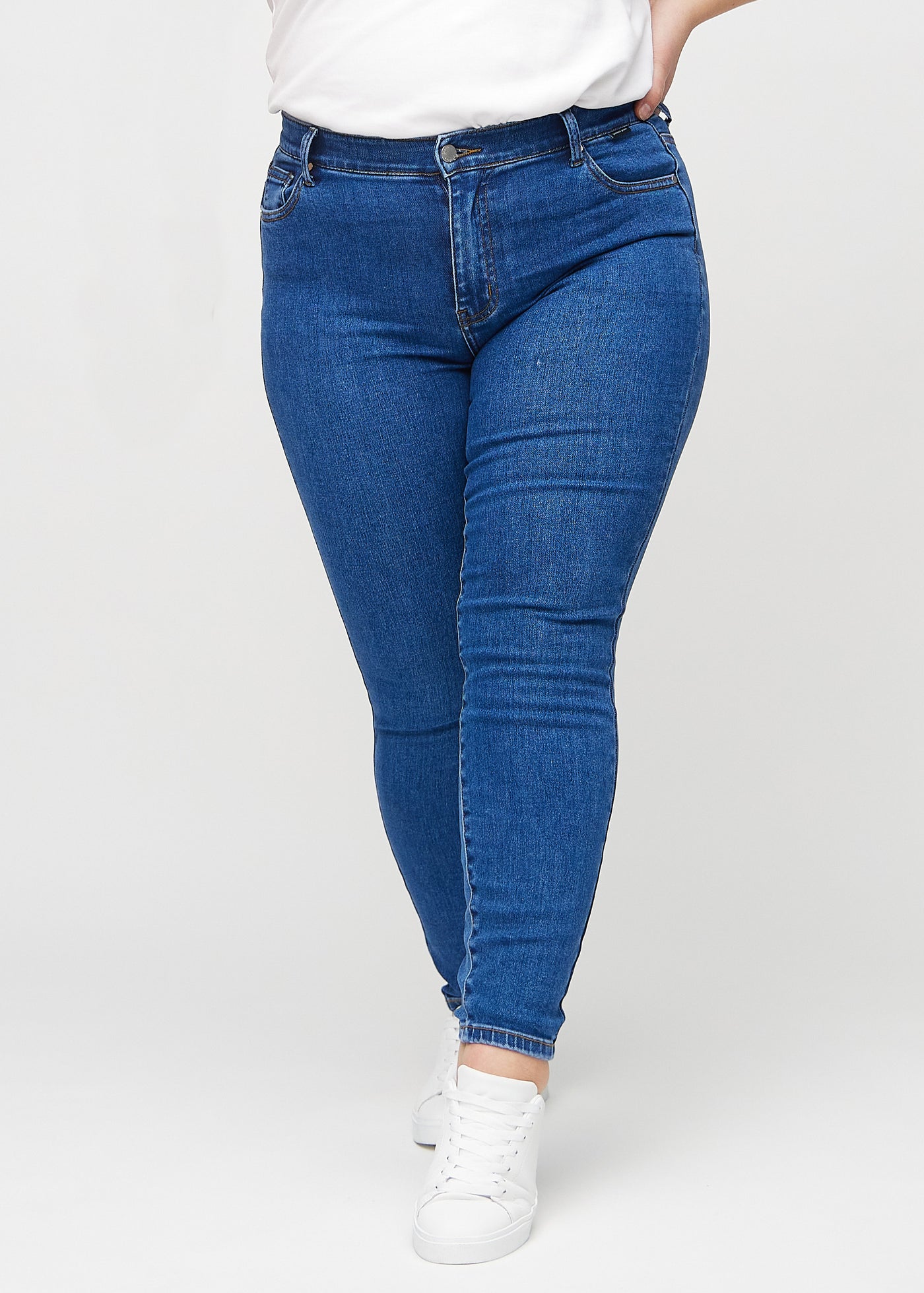 Mørk denim skinny jeans, modelnavn Oceans, som sidder tæt til benet på en plus-size model, set forfra.