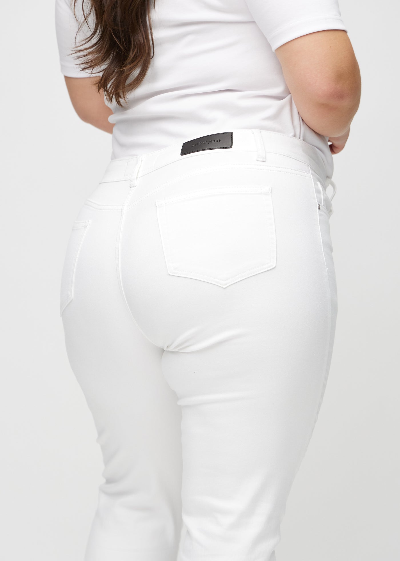 Hvide slim jeans set bagfra tæt på en plus-size model for at vise detaljer.