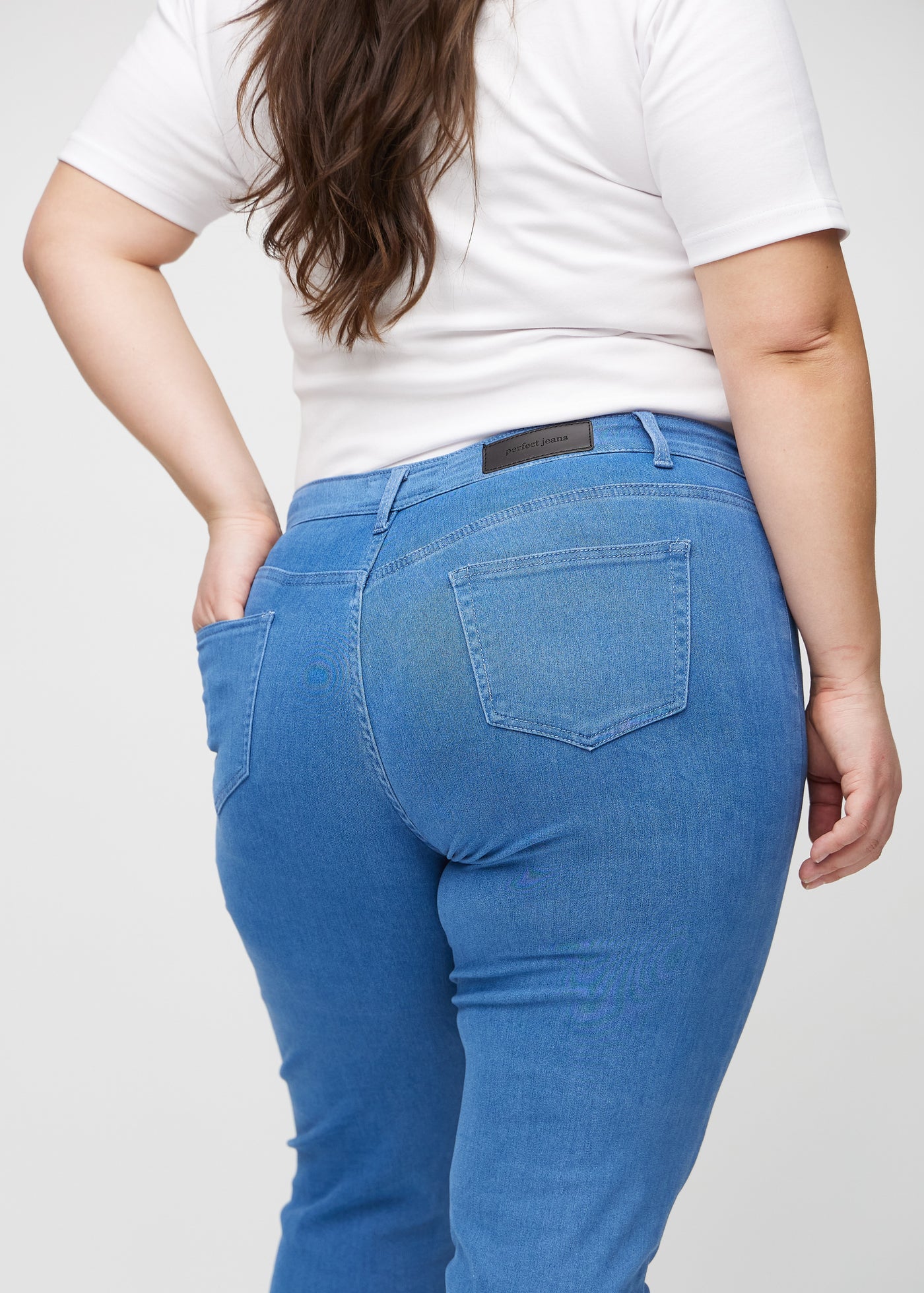 Blå slim jeans set bagfra tæt på en plus-size model for at vise detaljer.