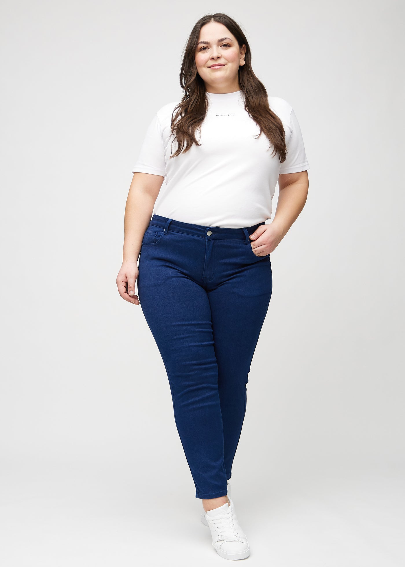 Fuldt billede af en plus-size model i mørkeblå slim jeans.