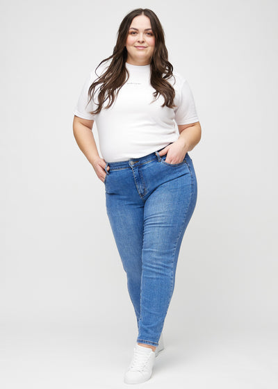 Fuldt billede af en plus-size model i denim slim ultra high rise jeans.