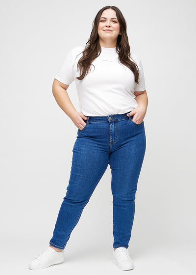 Fuldt billede af en plus-size model i mørk denim slim ultra high rise jeans.