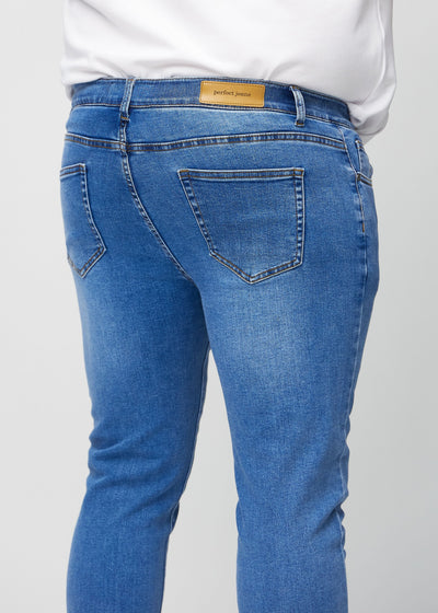 Denim slim jeans set bagfra tæt på en plus-size model for at vise detaljer.