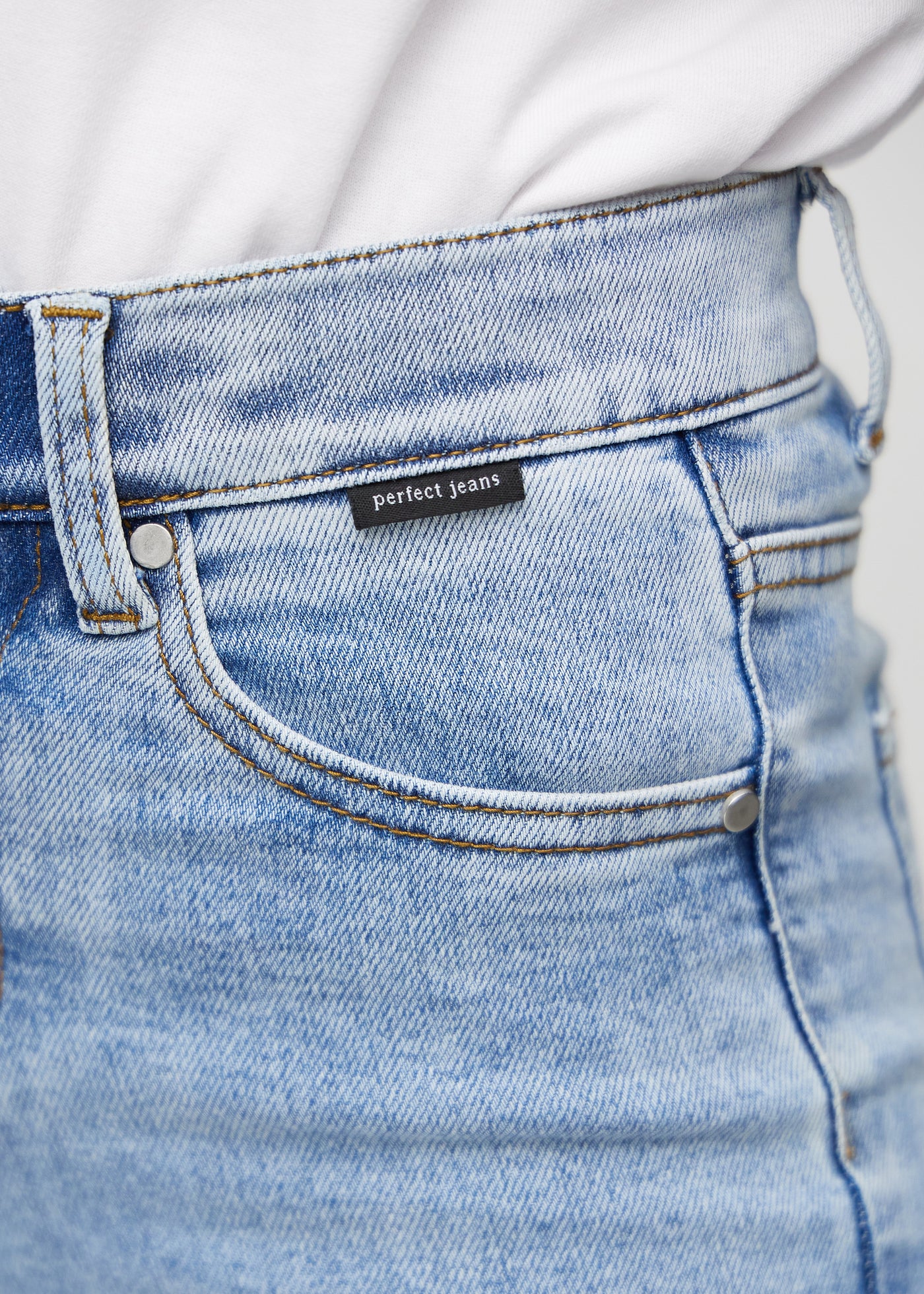 Forlommen på et par lys denim skinny middle shorts, hvor man kan se logoet.