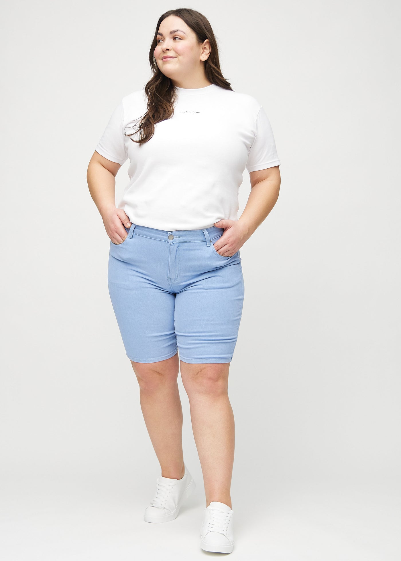 Plus-size model går ind i billedet, strækker i sine shorts, viser dem frem ved at dreje rundt, og forlader derefter billedet.