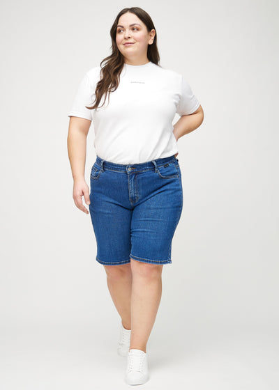 Plus-size model går ind i billedet, strækker i sine shorts, viser dem frem ved at dreje rundt, og forlader derefter billedet.