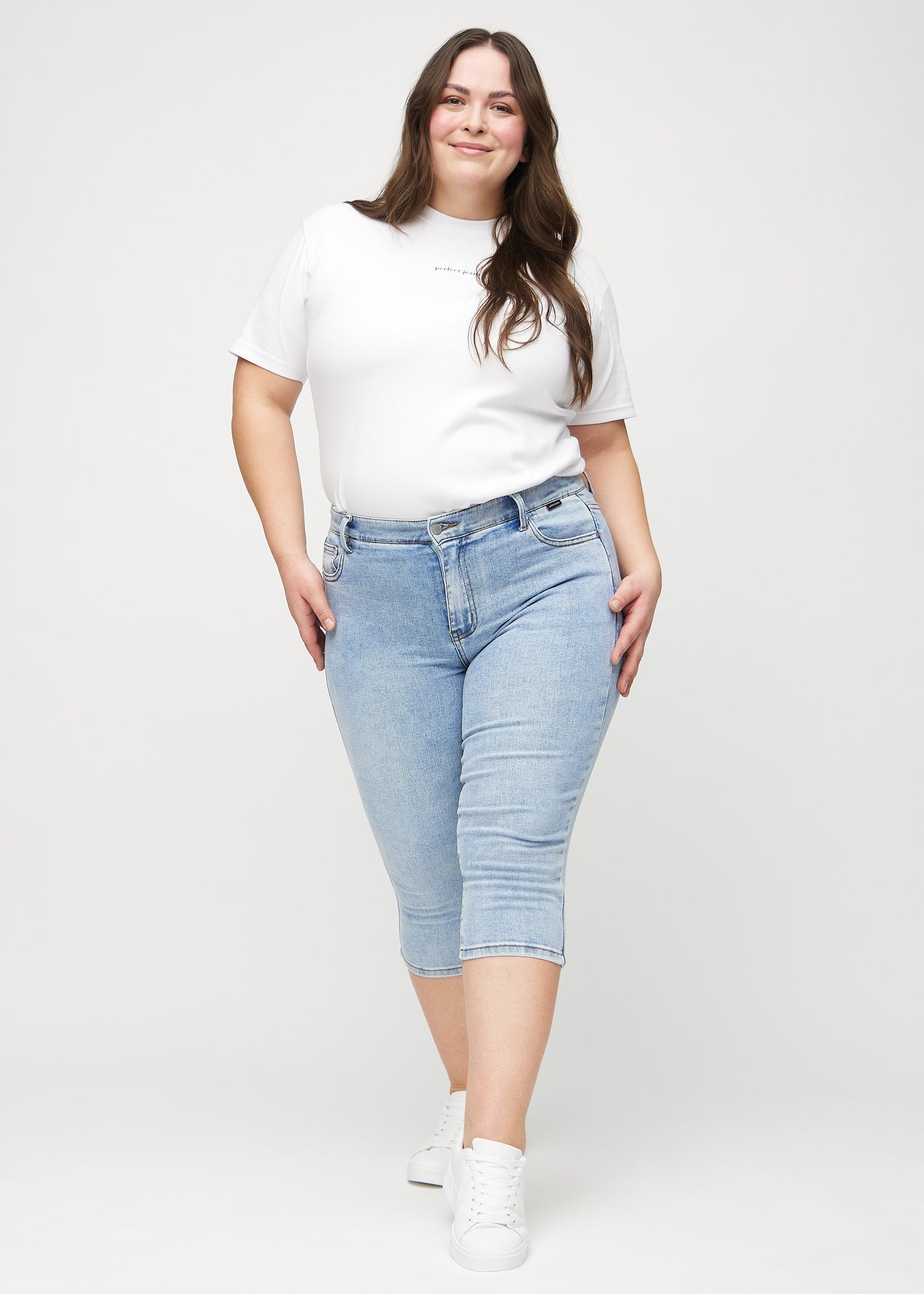 Plus-size model går ind i billedet, strækker i sine capris, viser dem frem ved at dreje rundt, og forlader derefter billedet.