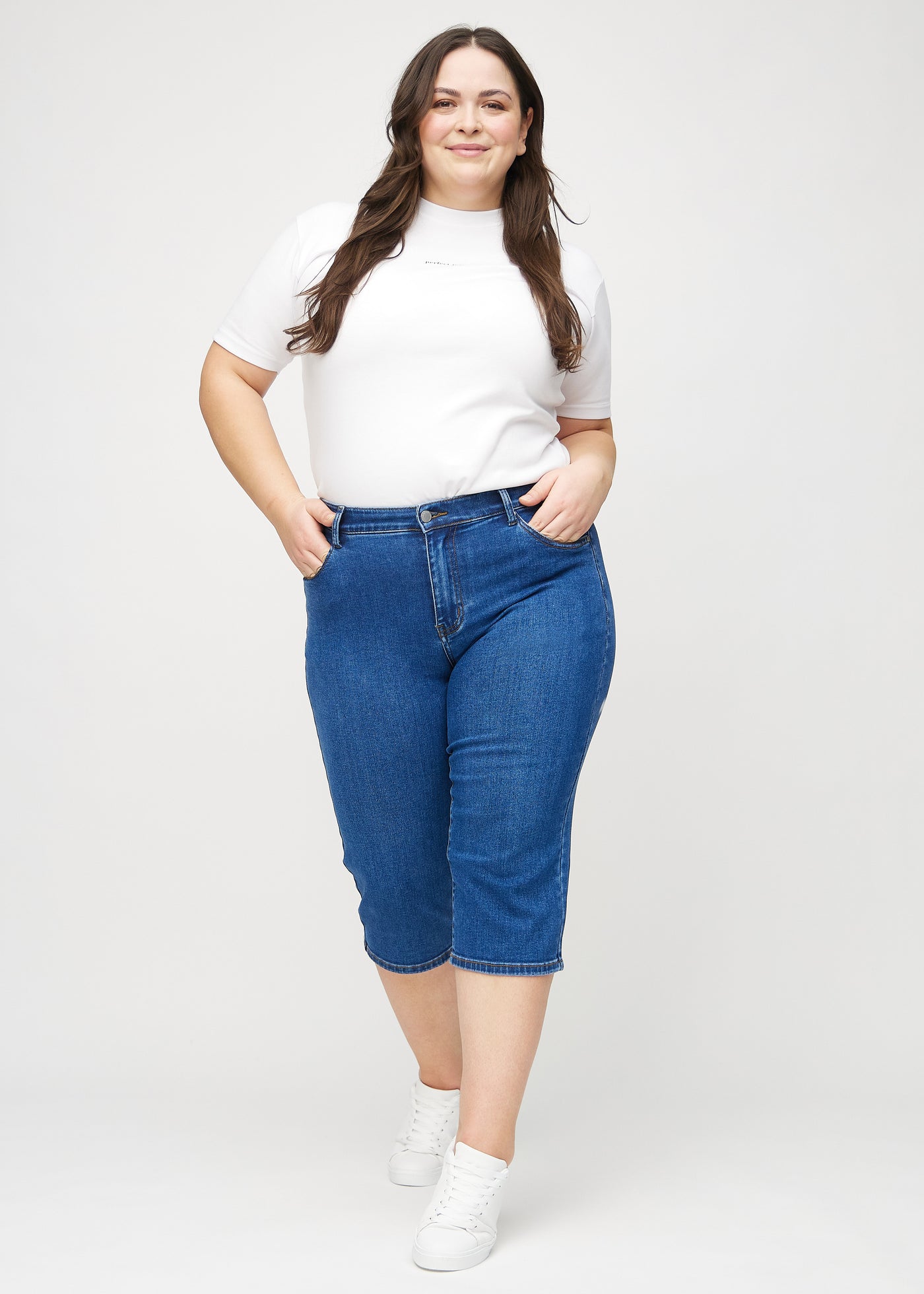 Plus-size model går ind i billedet, strækker i sine capris, viser dem frem ved at dreje rundt, og forlader derefter billedet.