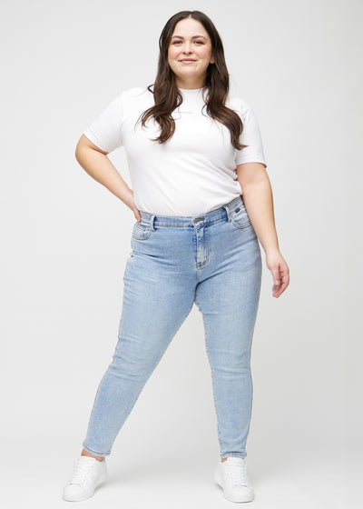 Plus-size model går ind i billedet, strækker i sine jeans, viser dem frem ved at dreje rundt, og forlader derefter billedet.